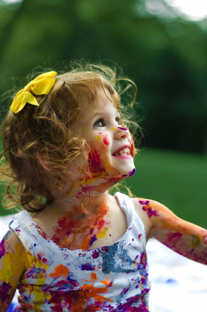 A child talking and covered in finger paint
