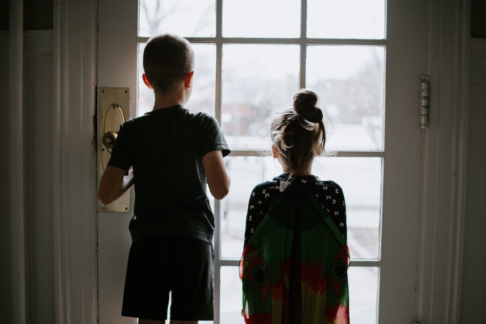 brother and sister looking out front door window