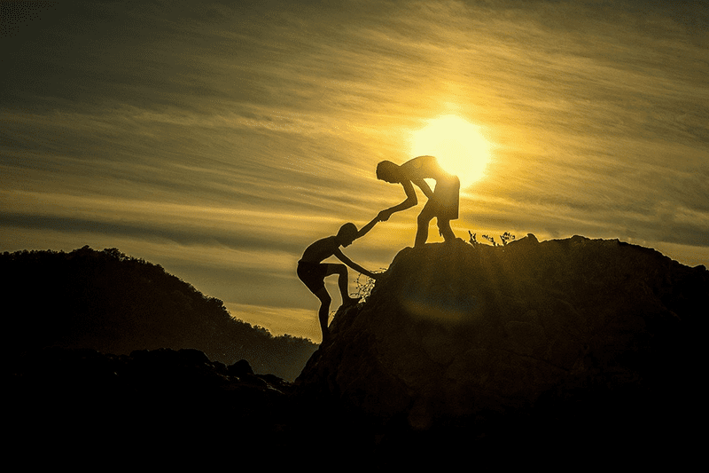 person helping someone up a hill