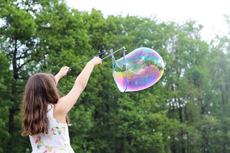girl blowing big bubble outside