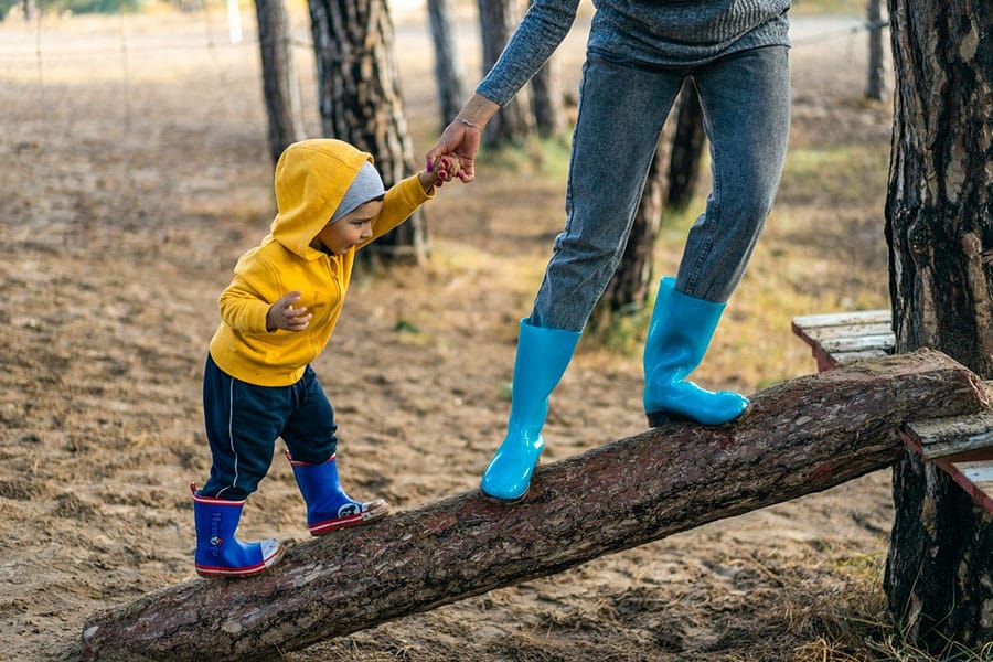 parent helping child balance on log
