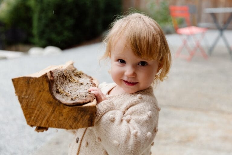 baby girl holding wood