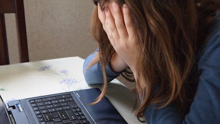 girl with head in hands over laptop